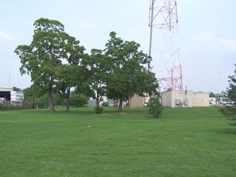 A grassy field with a large metal tower and a building in the background.