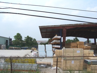 A large open building with a metal roof and construction supplies under and around it.