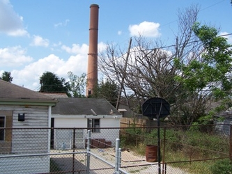 A fence in the foreground and trees in the background with residential homes in between.