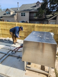 Man in a blue jacket bent over while inspecting equipment at a wastewater treatment plant