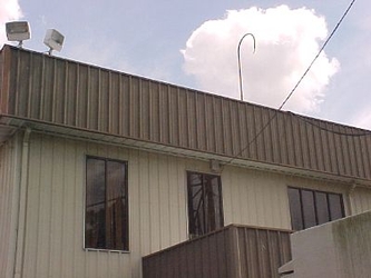 The top half of a tan building with brown accents and windows under a cloudy sky.