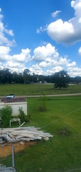 Grassland in the foreground and background, separated by a horizontal road in the middle, with trees in the far background and some residential buildings scattered throughout the view.